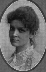 Atkinson is a young white woman with dark hair piled up on her head and a lacy blouse